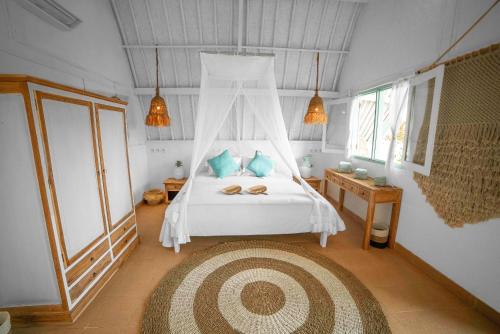 a bedroom with a white bed with a canopy at 7SEAS Cottages in Gili Islands