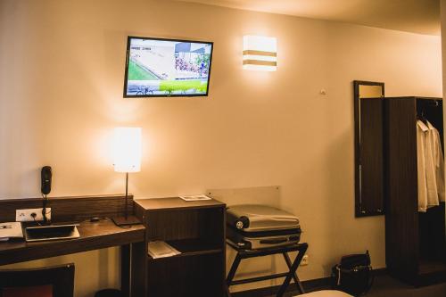 a room with a desk and a tv on the wall at DC Hotel Charleroi Airport in Charleroi