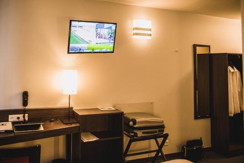 a room with a computer desk and a television at DC Hotel & Restaurant Charleroi Airport in Charleroi