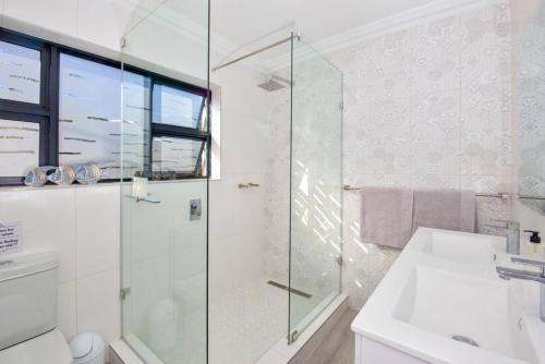a bathroom with a glass shower and a sink at Seacrest Cottage in Knysna