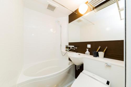 a white bathroom with a tub and a sink at M's Hotel Gojo Odawara in Kyoto