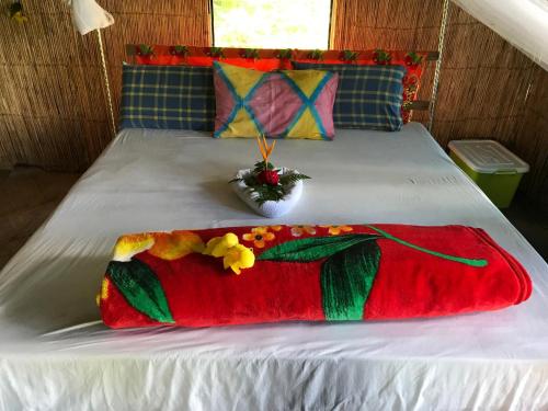 a bed with a red and green blanket on it at Lava View Tanna in Isaka