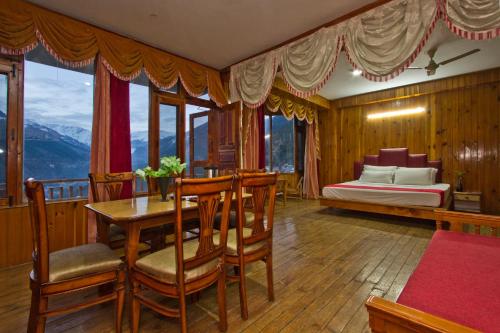 a bedroom with a table and chairs and a bed at Sarthak Resorts-Reside in Nature with Best View, 9 kms from Mall Road Manali in Manāli