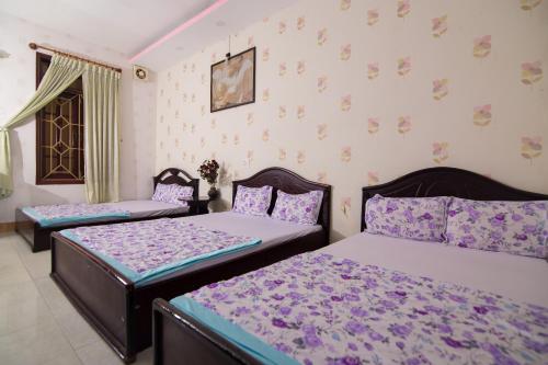 a bedroom with two beds with purple sheets at Hung Dong Hotel in Quy Nhon