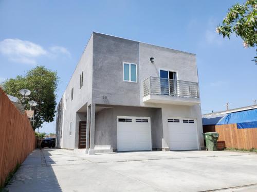 a gray building with two garage doors and a balcony at Modern Hostel address changed in Los Angeles