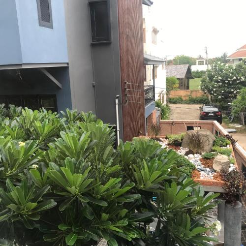 a garden in front of a building with plants at P.O.E Posh Homestay in Cha Am