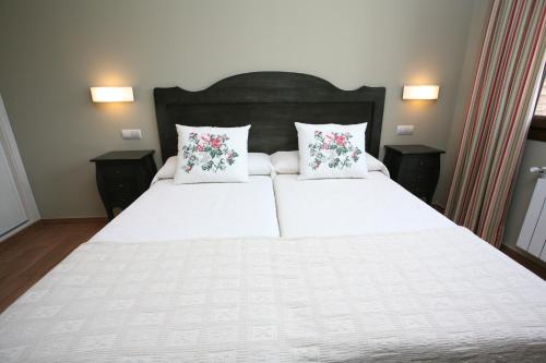 um quarto com uma grande cama branca e 2 almofadas em CASA RURAL MIRALTAJO em Corduente