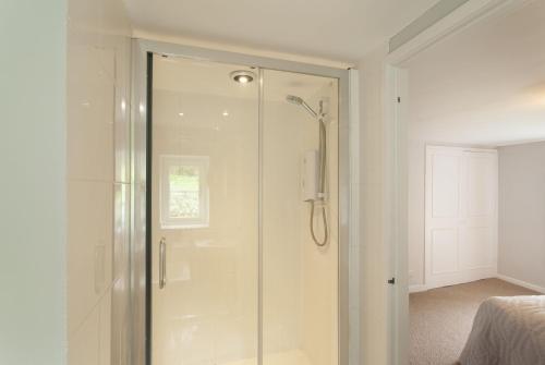 a bathroom with a shower with a glass door at Trinity Cottage, Roadwater in Nettlecombe