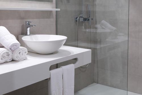 a bathroom with a sink and a glass shower at GHT S'Agaró Mar Hotel in Sant Feliu de Guixols