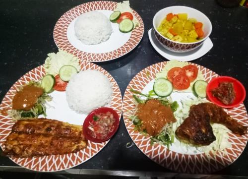 una mesa con platos de comida con carne y arroz en Jasri Dalem Surf Retreat en Jasri