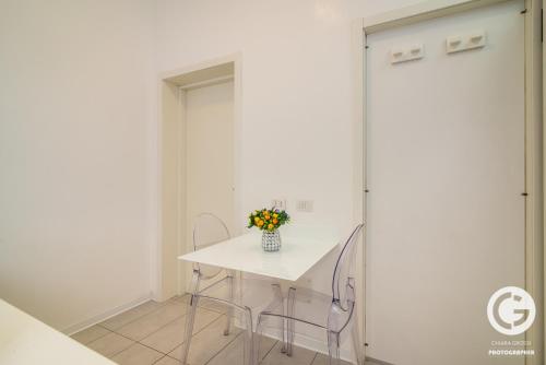 a white table and chairs with a vase of flowers on it at YPApartments FIERA in Padova