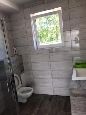 Elle comprend une petite salle de bains pourvue de toilettes et d'une fenêtre. dans l'établissement LEMA Pokoje Gościnne, à Skrzeszewo
