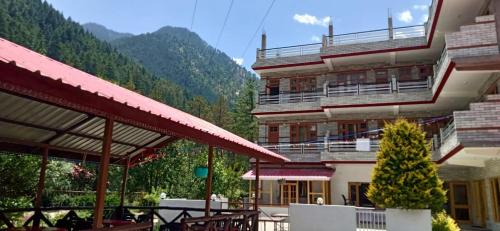 a large building with tables and chairs in front of it at The White House in Kasol