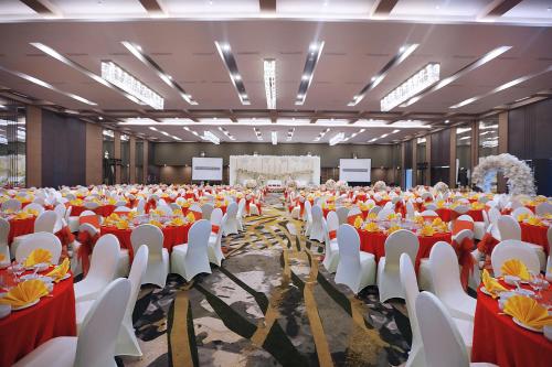 a large banquet hall with red and white tables and chairs at Harper Palembang by ASTON in Palembang
