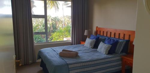 a bedroom with a bed with a blue comforter and a window at Ramsgate Palms Unit 20 in Ramsgate