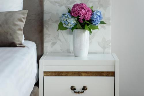 a white table with a vase of flowers on it at New Era Hotel Old Town Bucharest- parking with fee nearby - NOT at the hotel ! in Bucharest