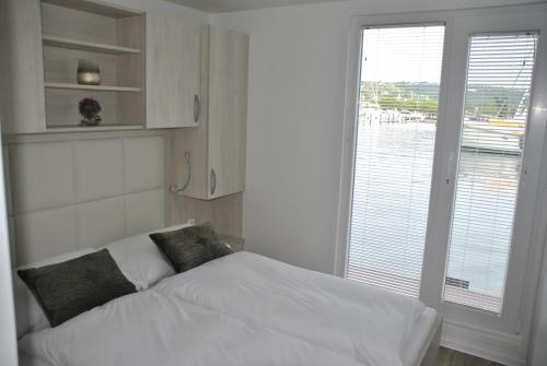 a white bed in a room with a large window at Marina seahouse Portorož in Lucija