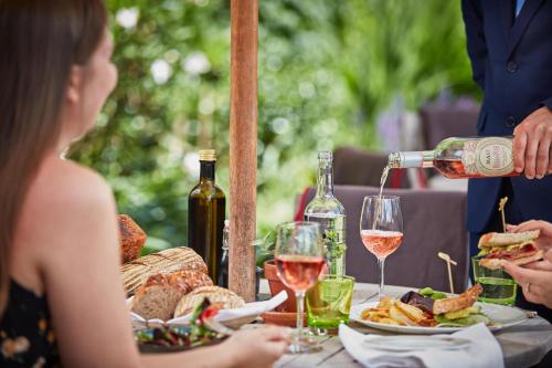 a man pouring a glass of wine on a table with food at Great Fosters - Near Windsor in Egham