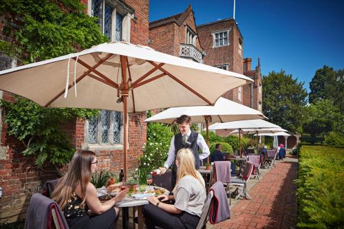 a group of people sitting at a table under an umbrella at Great Fosters - Near Windsor in Egham