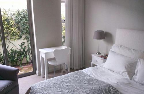 a bedroom with a bed and a desk and a window at 23 Grace in Cape Town