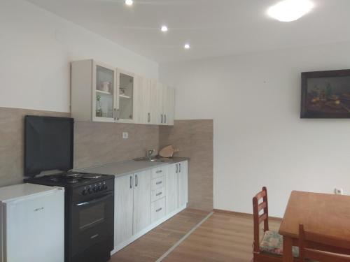 a kitchen with white cabinets and a stove and a table at Apartmani Alma in Skradin