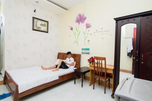 a young girl sitting on a bed in a room at Hung Dong Hotel in Quy Nhon