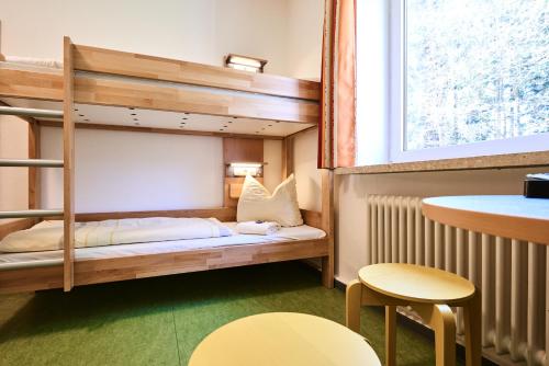 a bunk bed in a room with a table and chairs at DJH Jugendherberge Biggesee in Olpe