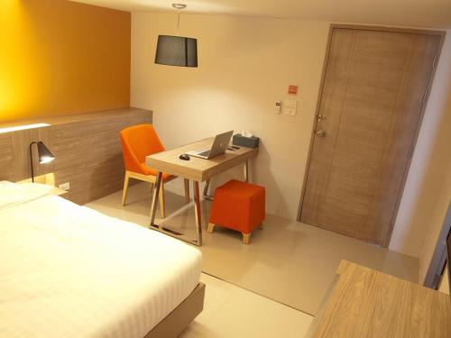 a hotel room with a bed and a desk with a laptop at ABIZZ Hotel Lampang Airport in Lampang