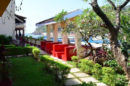 a gazebo with red chairs next to the beach at Baia Do Sol - Beach boutique in Baga