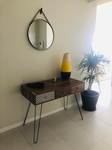 a table with a mirror and a plant on it at Kasa Imbondeiro in Mindelo