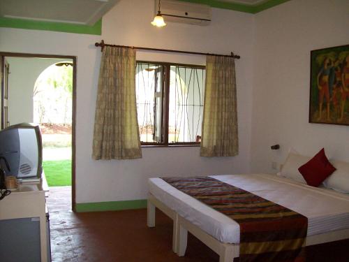 a bedroom with a bed and a tv and a window at Baia Do Sol - Beach boutique in Baga