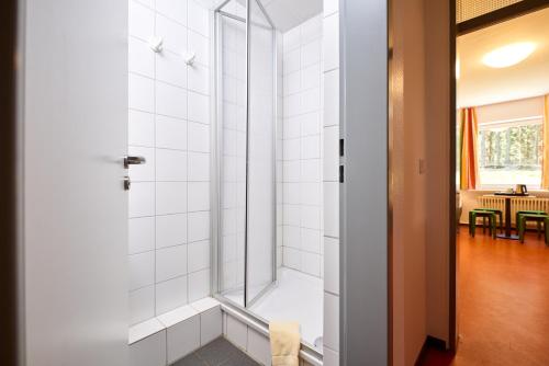 uma casa de banho com um chuveiro e uma porta de vidro em DJH Jugendherberge Biggesee em Olpe