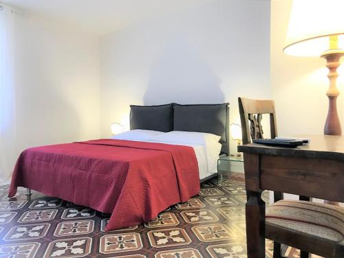 um quarto com uma cama com um cobertor vermelho e uma secretária em THE BLUE LODGE-cozy flat close to Piazza del Campo em Siena