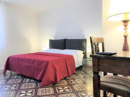 シエナにあるTHE BLUE LODGE-cozy flat close to Piazza del Campoのベッドルーム1室(赤毛布、デスク付)