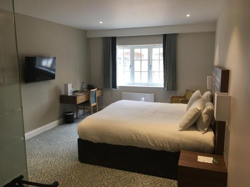 a hotel room with a large bed and a window at Quorn Grange Hotel in Loughborough