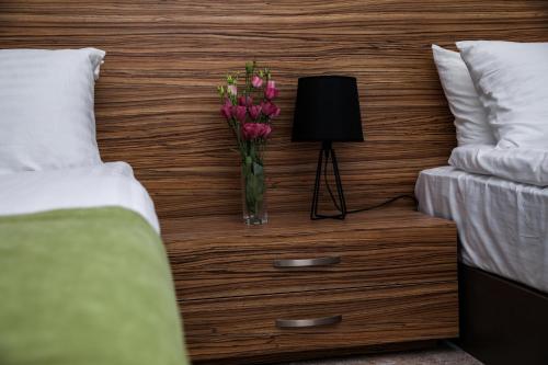 a vase of flowers on a nightstand next to two beds at Garden Inn Resort Sevan in Sevan