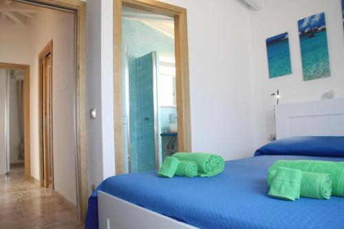 a bedroom with a blue bed with green towels on it at R House Budoni in Budoni