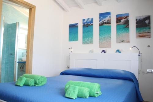 una camera con un letto blu e due asciugamani verdi di R House Budoni a Budoni