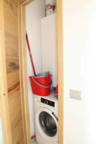 a washing machine with a red bucket on top of it at R House Budoni in Budoni