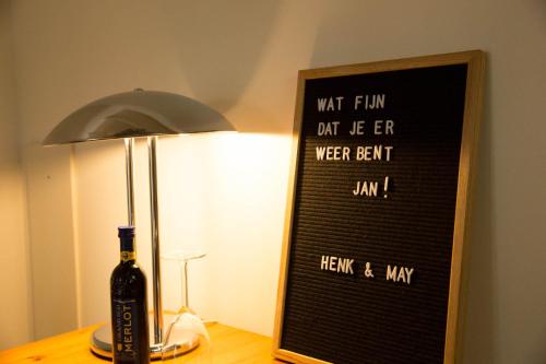 a bottle of wine next to a lamp and a sign at Beej Potters in Weert
