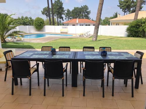 a black table with chairs and a pool at Villa near Beach & Lisbon in Corroios