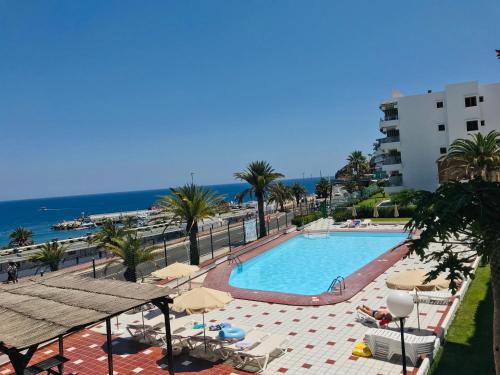 una piscina con sedie e ombrelloni e l'oceano di Puertorico Tobago Happy Paradise a Puerto Rico de Gran Canaria