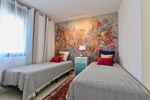 ベニドルムにあるMirador del Mediterraneoのベッドルーム1室(ベッド2台付)が備わります。壁には絵画が飾られています。