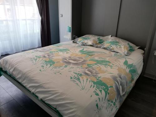 a bed with a floral comforter and pillows at Lyloo Studio Epernay in Épernay