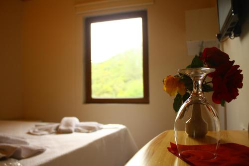 un jarrón de flores sobre una mesa con una ventana en Uyku Vadisi Hotel, en Ağaçlıhüyük