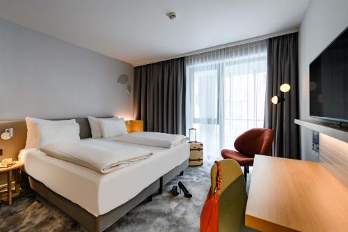 um quarto de hotel com uma cama e uma televisão em Mercure Hotel München-Schwabing em Munique