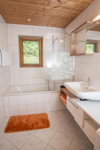 a white bathroom with a tub and a sink at Alpsapart Regina in Schwendau