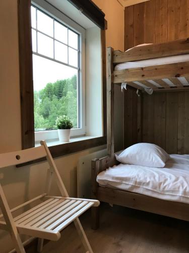a bedroom with a bunk bed and a chair and a window at Kvamseter Lodge - Mountain Apartments in Norheimsund