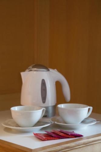 a tea kettle and two white bowls on a table at Thermenhotel Quellenhof in Bad Füssing