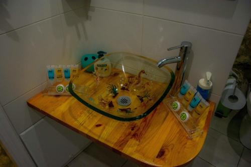 Limni Stone Apartments في Límni: حوض الحمام مع وعاء زجاجي على منضدة خشبية